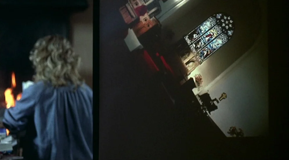 Don’t Look Now (1973) movie still: medium — A dimly lit room contains a person watching a tilted projection of a church interior. The projection…