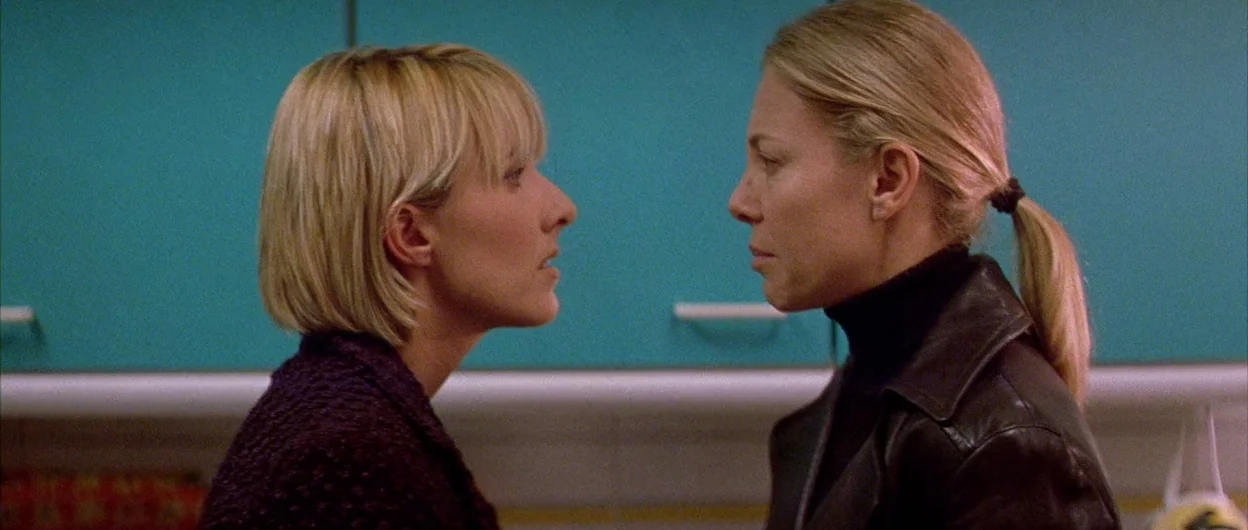 All About My Mother (1999) movie still: medium — A kitchen with bright teal cabinets serves as the background for two women. The women stand facing…