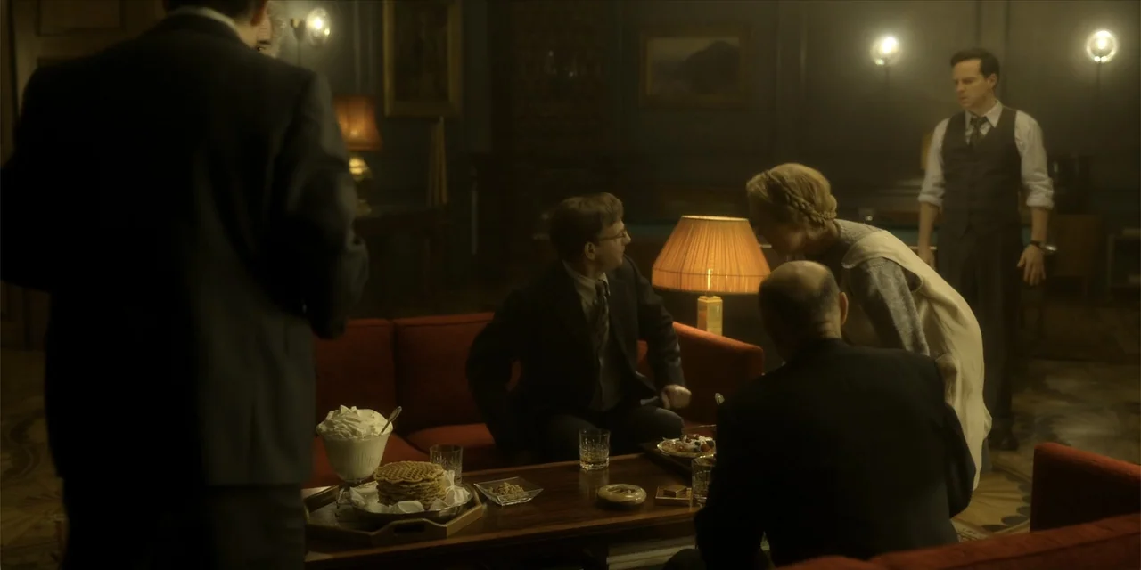 Oslo (2021) movie still: medium — A dimly lit 1950s lounge contains dark red velvet sofas and a low wooden table. A group of adults gather around…