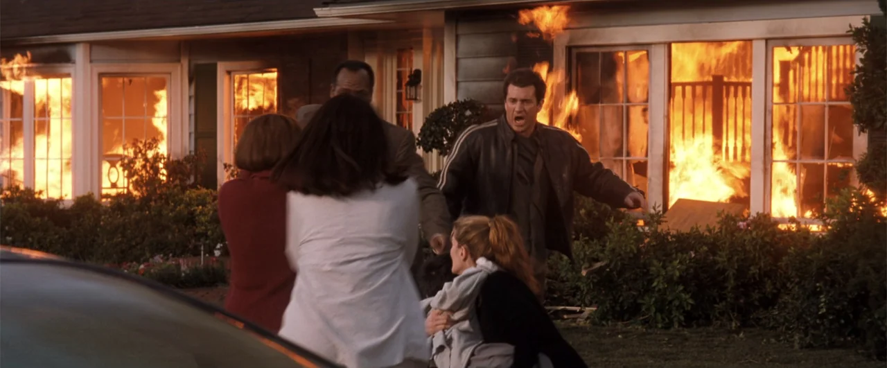 Lethal Weapon 4 (1998) movie still: medium — A burning residential house with flames visible through large windows stands behind a front lawn. A…