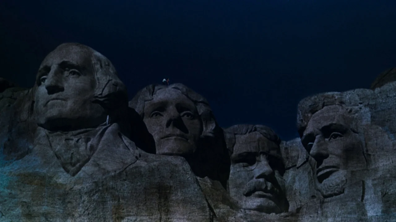 North By Northwest (1959) movie still: wide — The monumental stone carvings of American presidents are set against a dark night sky. Massive granite…