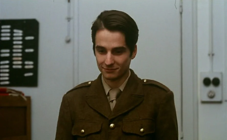 Stolen Kisses (1968) movie still: medium — A plain administrative room features white walls, a filing board, and an electrical switch. A young man…