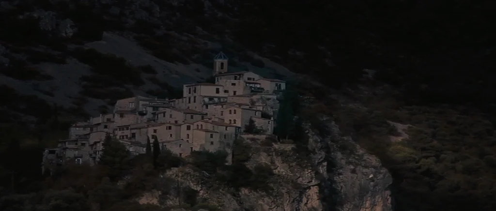 You Ain’t Seen Nothin’ Yet (2012) movie still: establishing — A cluster of stone buildings clings to the side of a jagged mountain cliff. The…