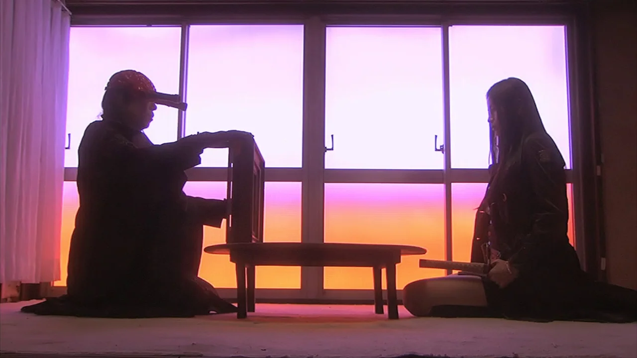 Tokyo Gore Police (2008) movie still: wide — A minimalist room features a platform facing a large window with vibrant sunset light. Two figures in…