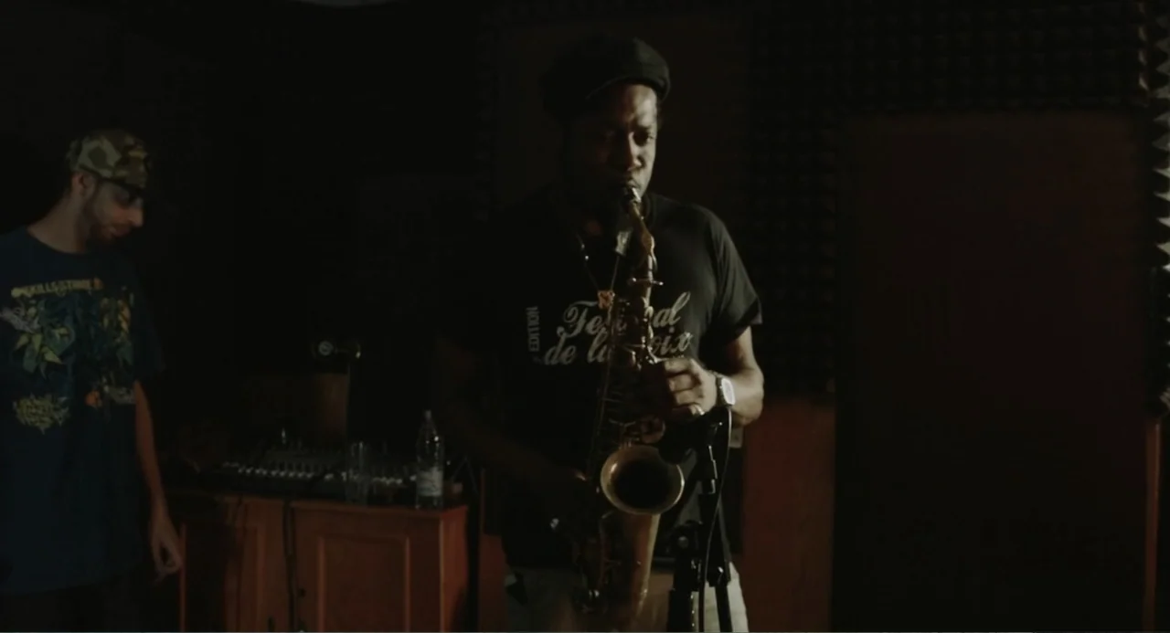 Cairo Jazzman (2017) movie still: medium — A dimly lit recording studio features acoustic wall panels and professional audio equipment. A musician…