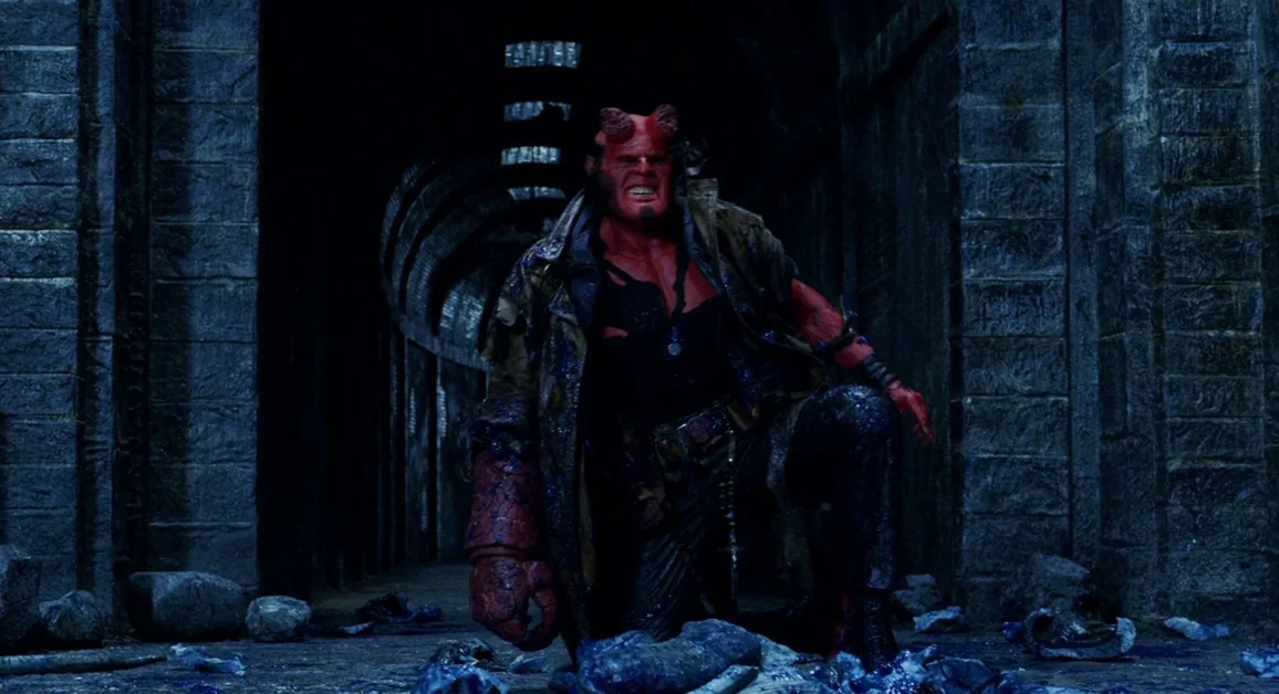 Hellboy (2004) movie still: fullbody — A dark subterranean corridor constructed from heavy rectangular stone blocks leads into deep shadows. A large…