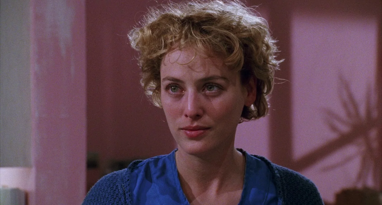 Candyman (1992) movie still: closeup — A woman stands in a room with soft pink walls and structured architectural shadows. She looks ahead in a…