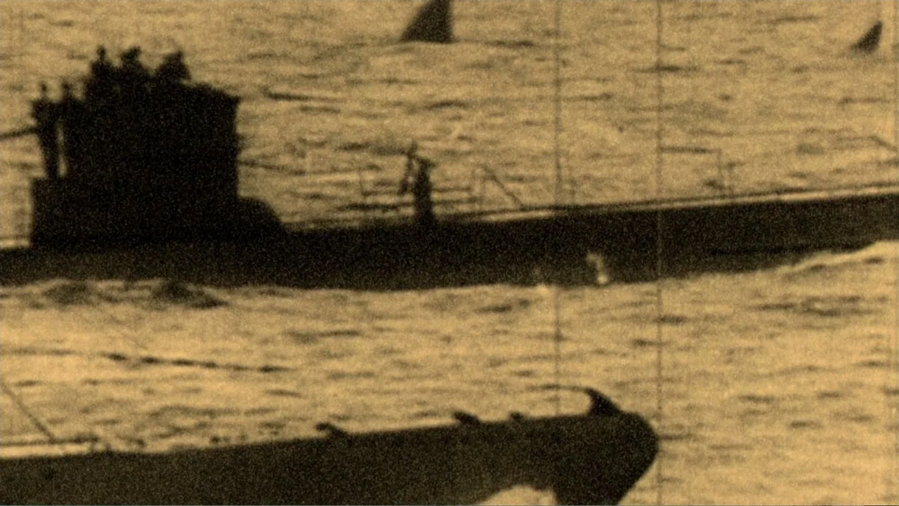 Megalodon: The Monster Shark Lives (2013) movie still: wide — A dark submarine silhouette travels across a textured, light-toned ocean surface in…