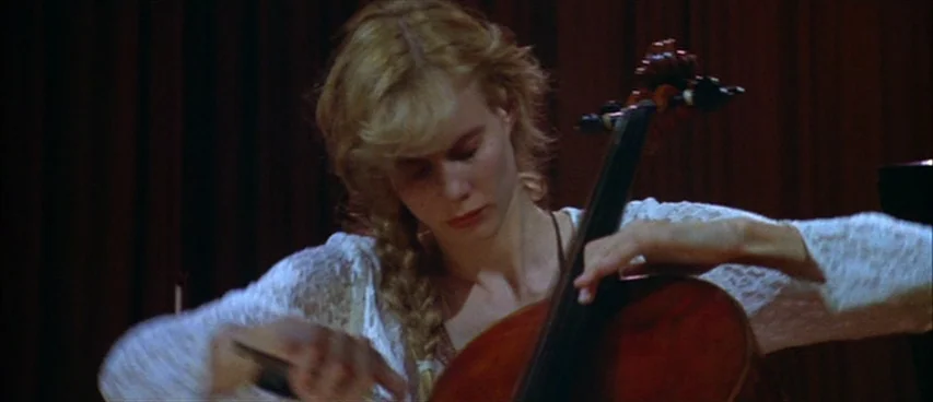 Short Cuts (1993) movie still: medium — A woman plays a cello against a backdrop of heavy dark curtains. She is dressed in a white lace blouse while…