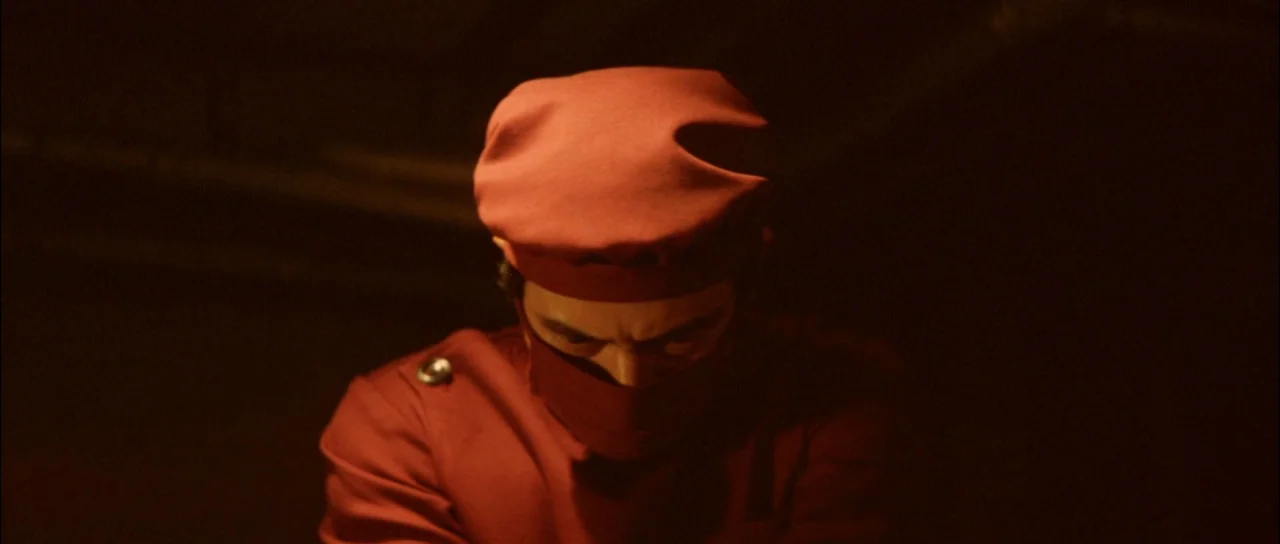 Terror of Mechagodzilla (1975) movie still: medium — A dark, dimly lit environment features a person in maroon medical attire. A medical…