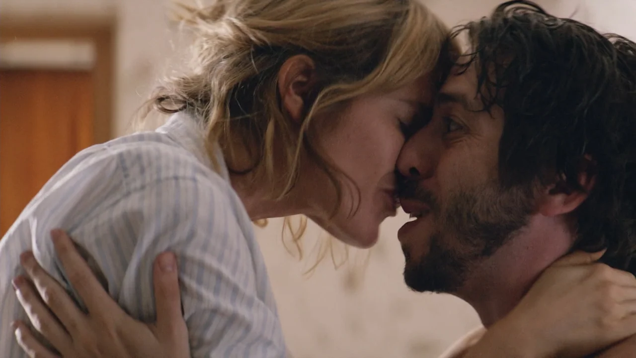 That's Not Cheating (2016) movie still: closeup — A light-filled interior bedroom with muted walls and soft textures. A man and a woman are kissing…