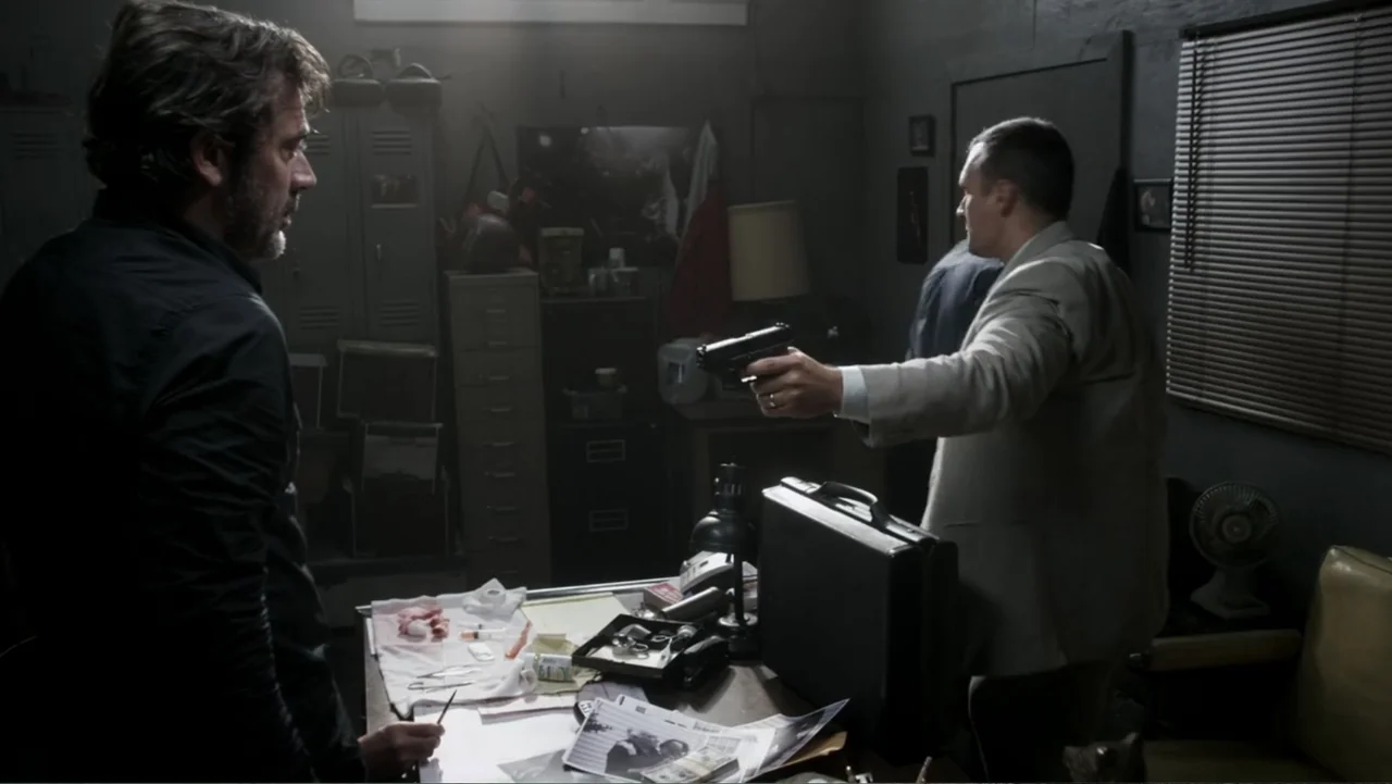 The Messenger (2015) movie still: medium — A cluttered small office contains a metal desk covered in medical supplies and papers. A man stands…