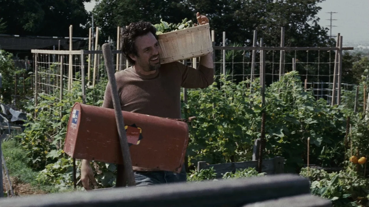 The Kids Are All Right (2010) movie still: medium — A man walks through a lush vegetable garden filled with various green leafy plants. He carries a…