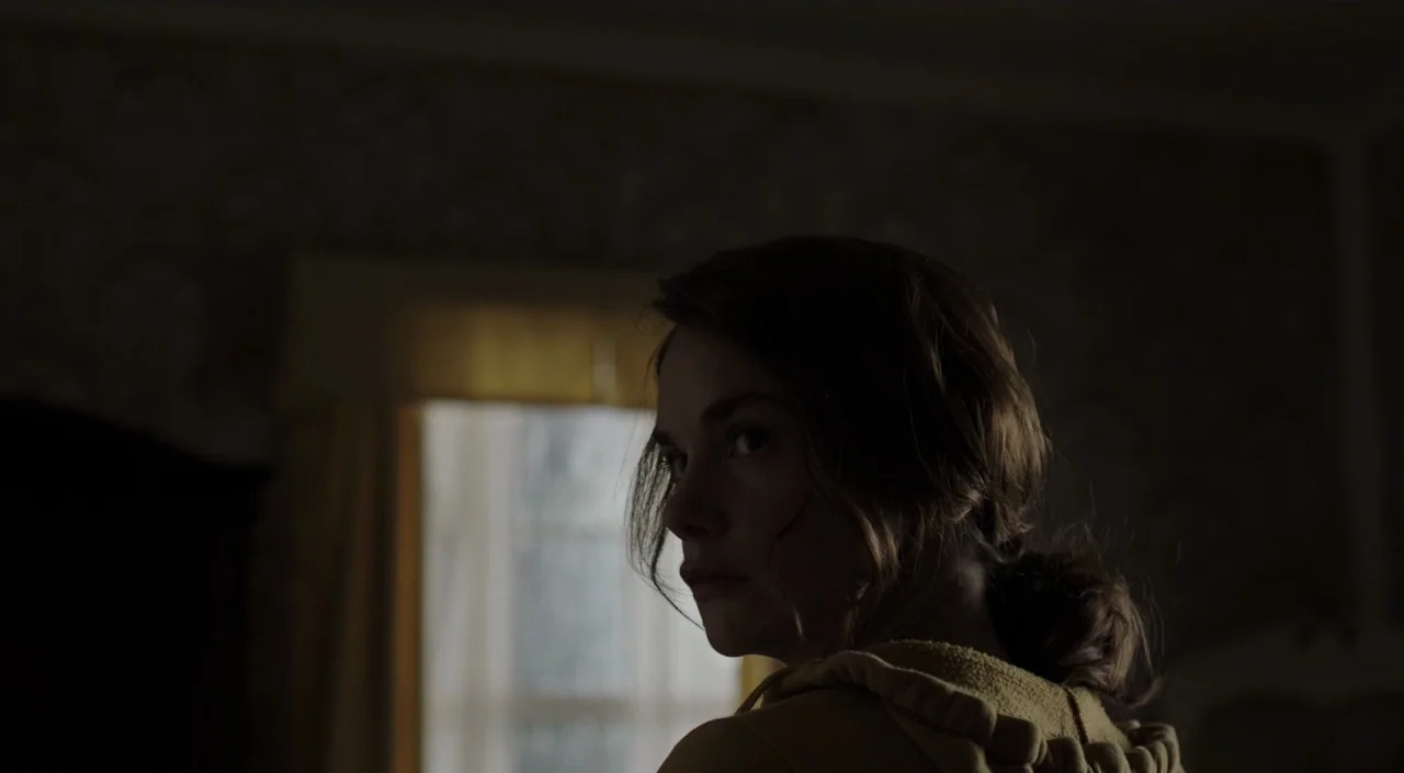 I Am The Pretty Thing That Lives In The House (2016) movie still: closeup — A dimly lit room features patterned wallpaper and a window with light…