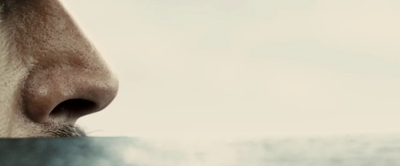 Pirates of the Caribbean: At World’s End movie still: closeup — A man's face is partially submerged in a vast expanse of water. Only the nose and a…