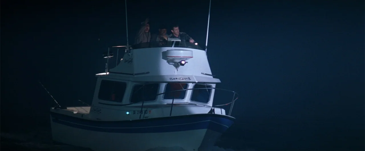 Lethal Weapon 4 (1998) movie still: fullbody — A white fishing boat travels through dark water at night with lights on top. Three men stand on the…