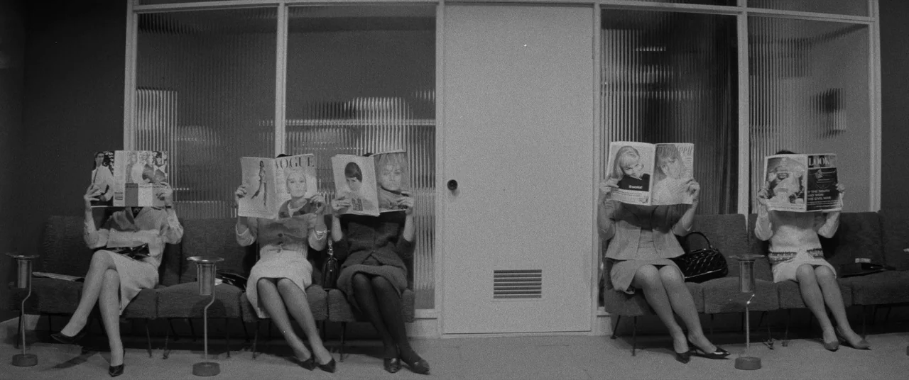 Carmen From Kawachi (1966) movie still: wide — A minimalist mid-century waiting room featuring a bench against a ribbed glass wall divider. Five…