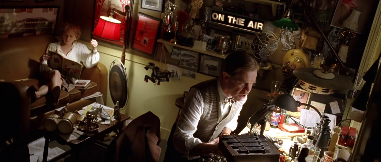 Seabiscuit (2003) movie still: wide — A cluttered 1940s radio room is packed with posters, trophies, and vintage audio equipment. A man sits at a…