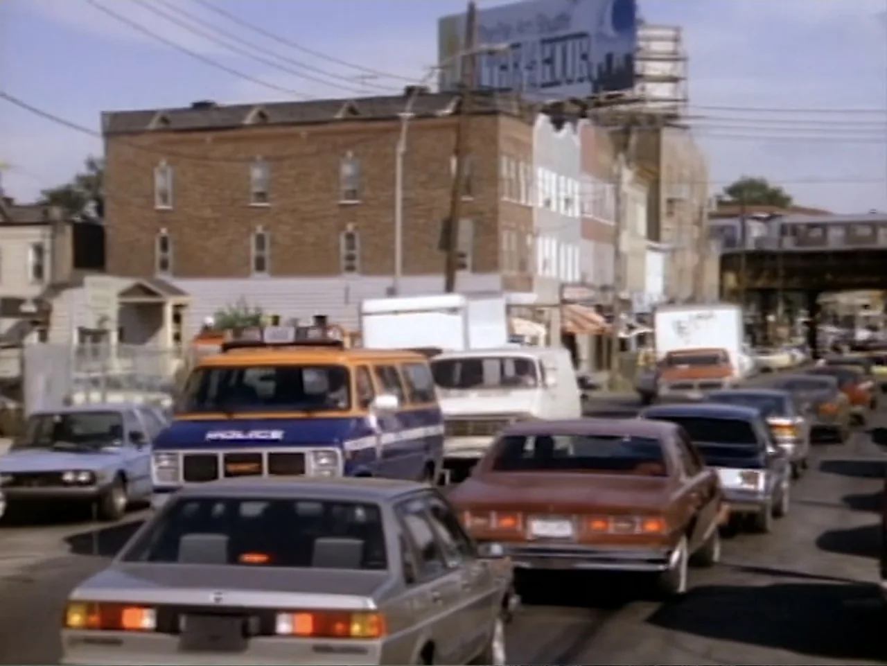 My First Love (1988) movie still: wide — A busy urban street is filled with a congestion of vintage cars and trucks. A brown brick building stands…