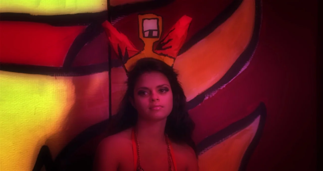 Adam Green’s Aladdin (2016) movie still: medium — A woman stands before a large, hand-painted wall mural depicting stylized orange and yellow…