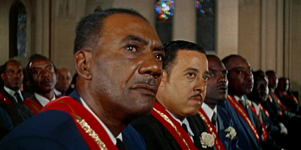 Imitation of Life (1959) movie still: medium — A group of men sit in church pews wearing formal regalia and sashes. They look toward the front…