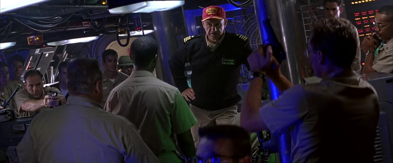 Crimson Tide (1995) movie still: medium — A cramped military submarine control room features circular metal bulkheads and glowing console displays.…