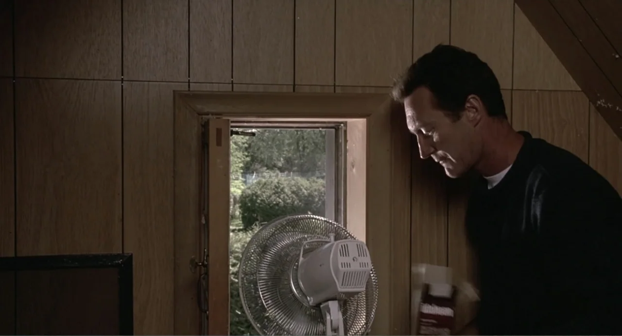 F/X2 (1991) movie still: medium — An attic room features wood-paneled walls and a small open window facing outdoors. A man in a dark sweater stands…