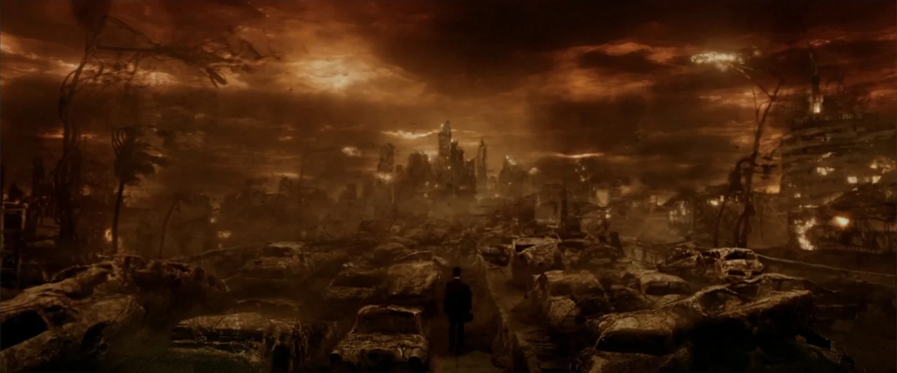 Constantine (2005) movie still: wide — A destroyed city landscape lies in ruins with numerous charred vehicles scattered throughout. A lone man in a…