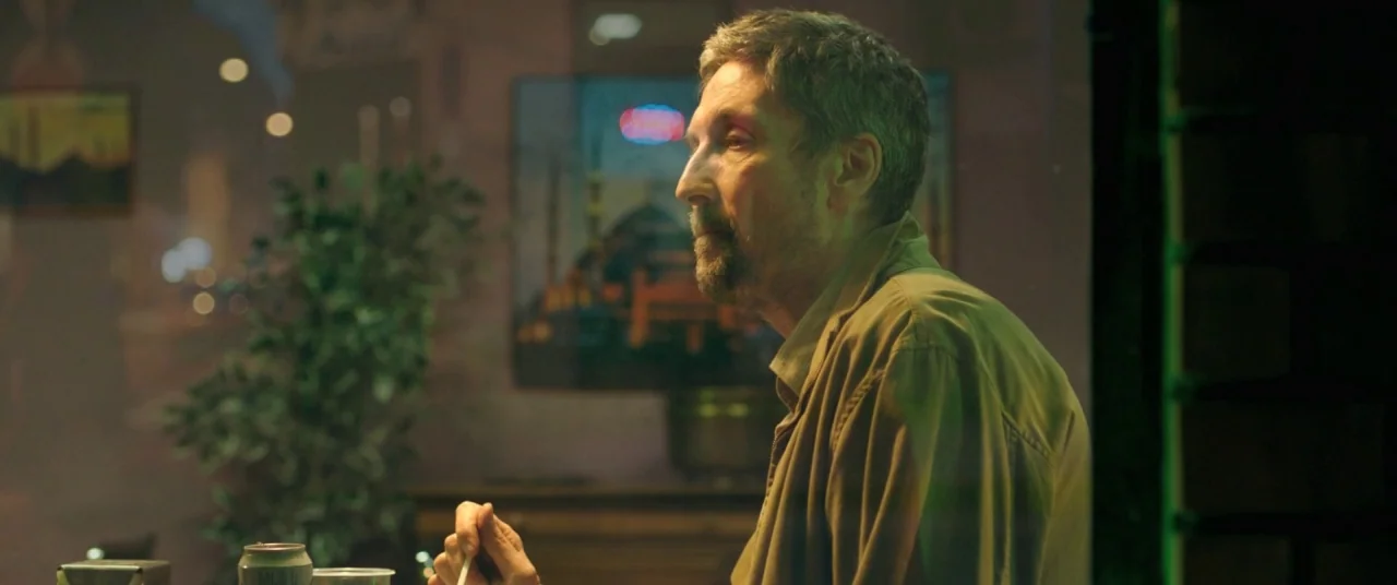 On Body and Soul (2017) movie still: medium — A dimly lit diner booth at night with a large window reflecting street lights. A man sits at the table…