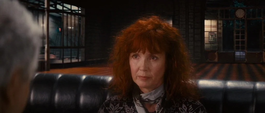 You Ain’t Seen Nothin’ Yet (2012) movie still: medium — A dimly lit train station waiting area features a dark leather bench. A woman with curly red…