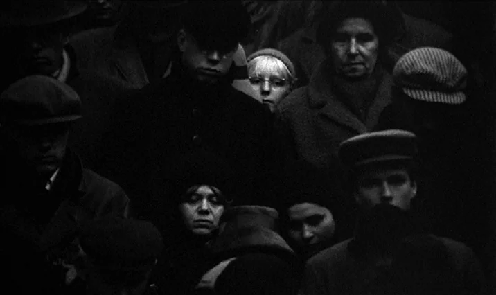 The Serpent’s Egg (1977) movie still: medium — A dense, dark crowd of people stands together outdoors in a monochromatic environment. Multiple…