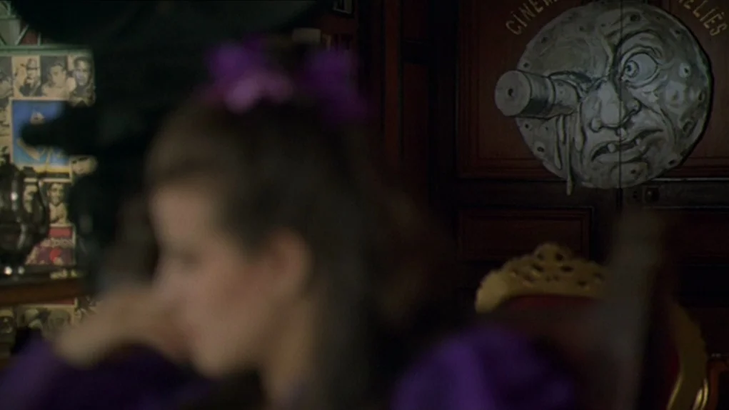 One Hundred and One Nights (1995) movie still: medium — A dark study wall features a decorative plaster moon with a telescope in its eye. A woman in…