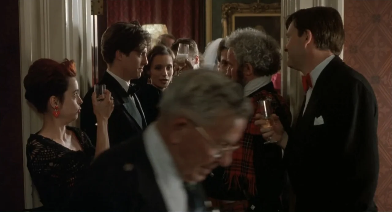 Four Weddings and a Funeral (1994) movie still: medium — A crowded formal event features people standing close together in a paneled interior space.…
