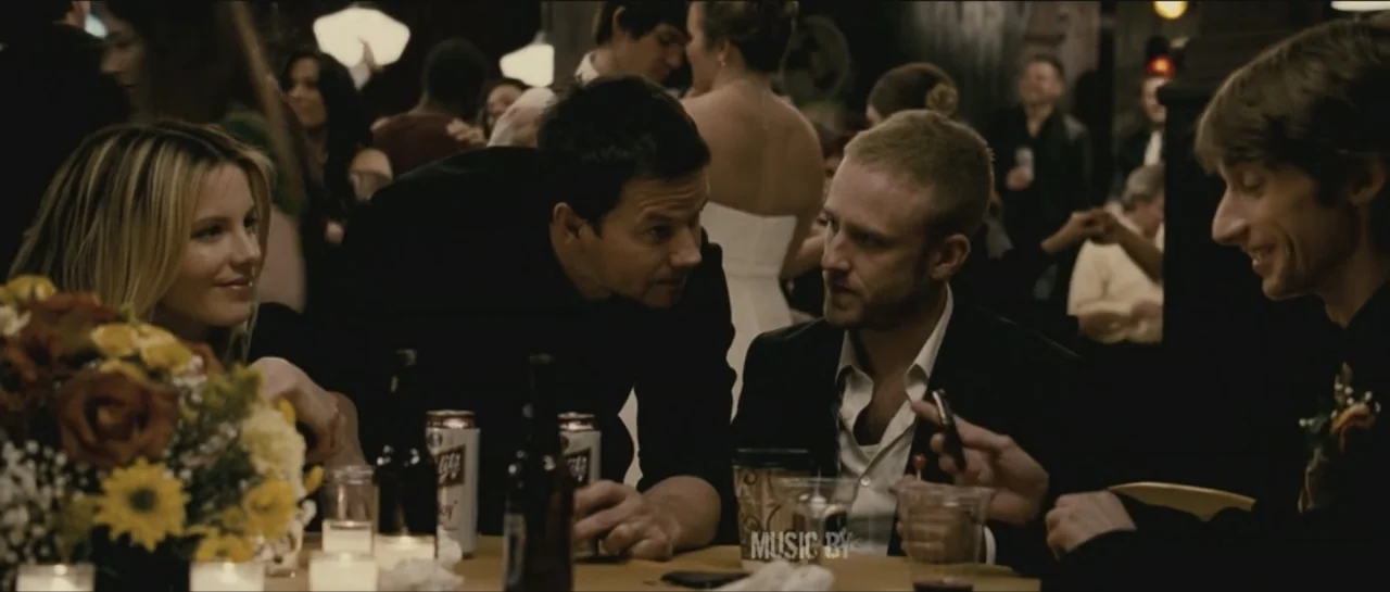 Contraband (2012) movie still: medium — A crowded banquet hall features guests sitting around tables in a dimly lit space. Four people converse at a…