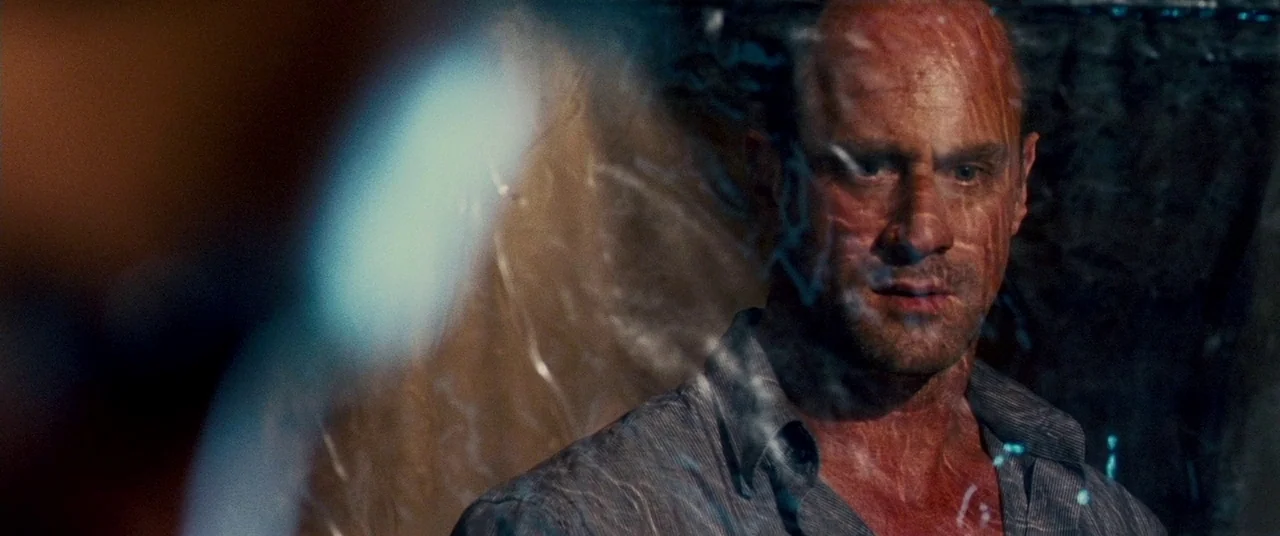 Carriers (2009) movie still: medium — A man stands behind a distorted, translucent material that warps his features. He stares forward while the…