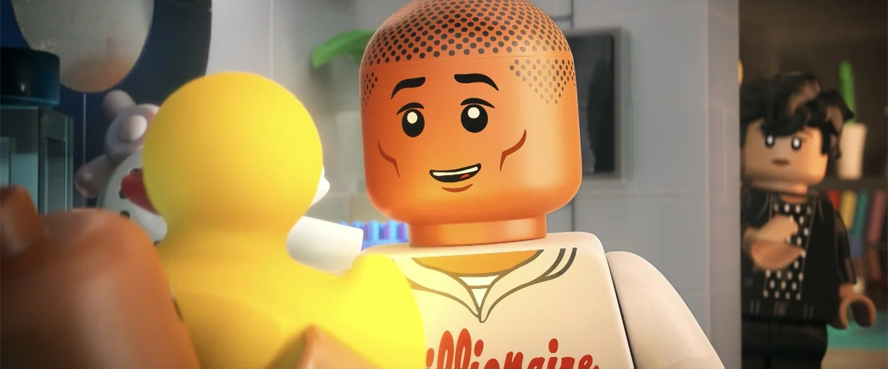 Piece by Piece (2024) movie still: medium — A brightly lit interior bathroom features tiled walls and a yellow rubber duck. A lego man faces the…