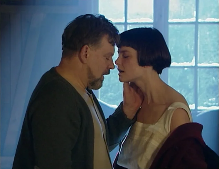 In The Presence of a Clown (1997) movie still: medium — A sparsely furnished room is illuminated by bright daylight coming through a large window. A…