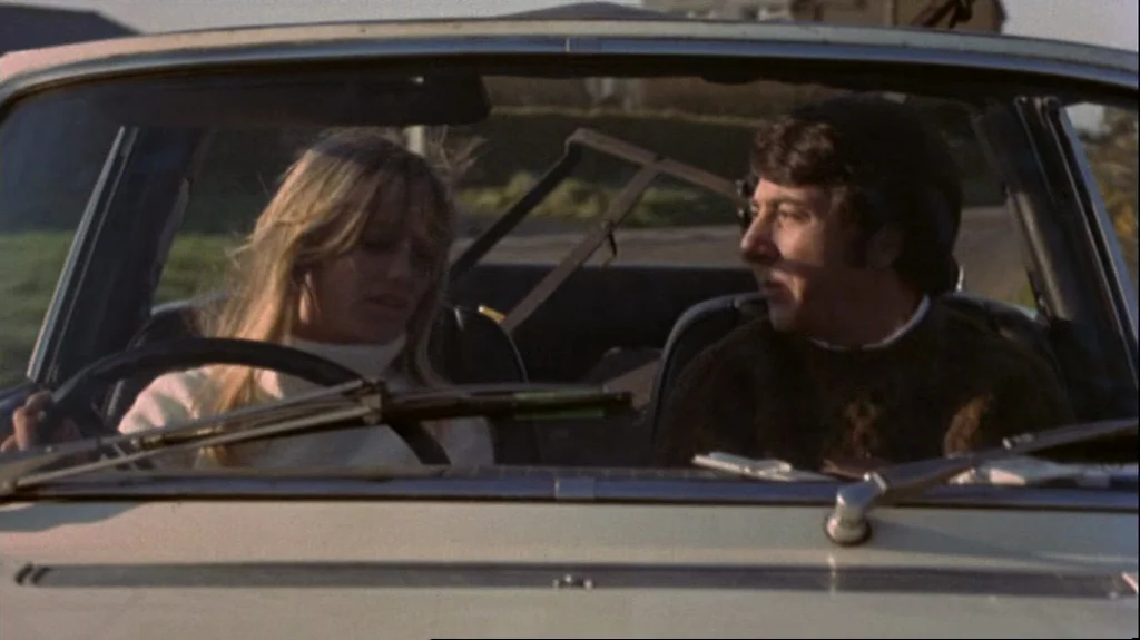 Straw Dogs (1971) movie still: medium — Two people sit inside a convertible car with the top down. The man and woman face each other while driving.