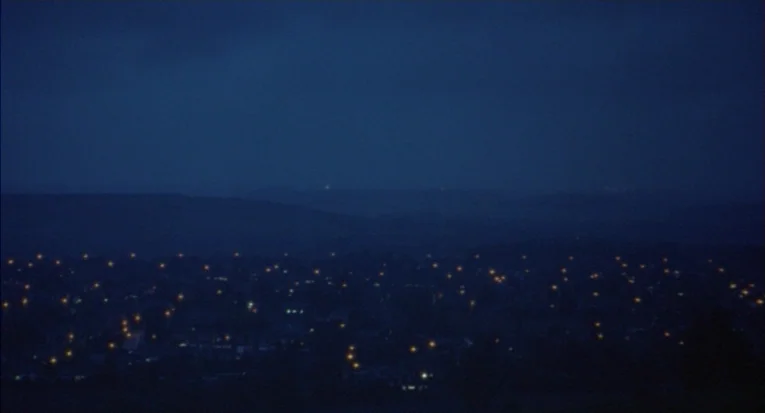 A Room For Romeo Brass (1999) movie still: establishing — A dark, hilly landscape overlooks a sprawling urban expanse at deep night. The city grid…