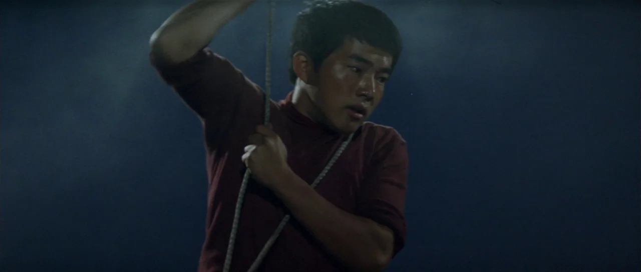 Ebirah Horror of the Deep (1966) movie still: medium — A man stands in a dark environment holding a vertical rope in his hands. He is positioned…