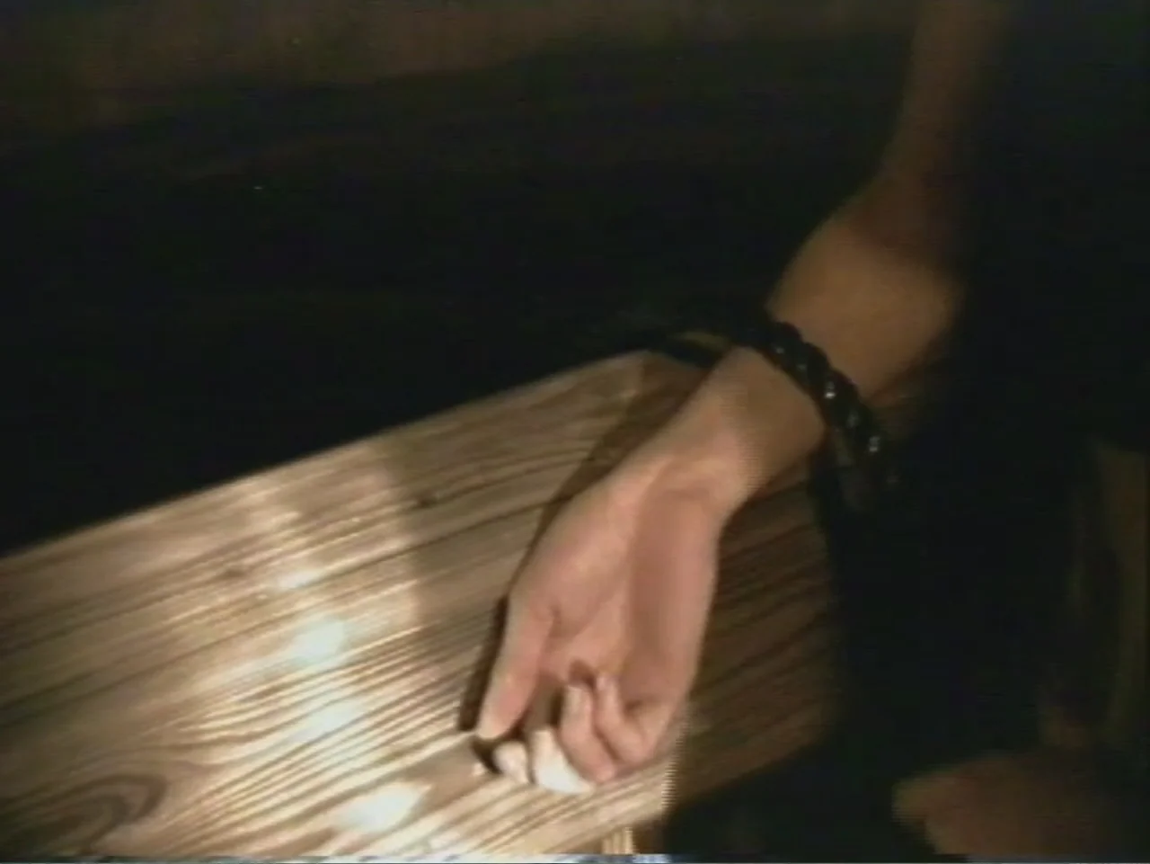Dracula, Prisoner of Frankenstein (1972) movie still: closeup — A close-up shot focuses on a wooden surface inside a dark room. A person's hand…