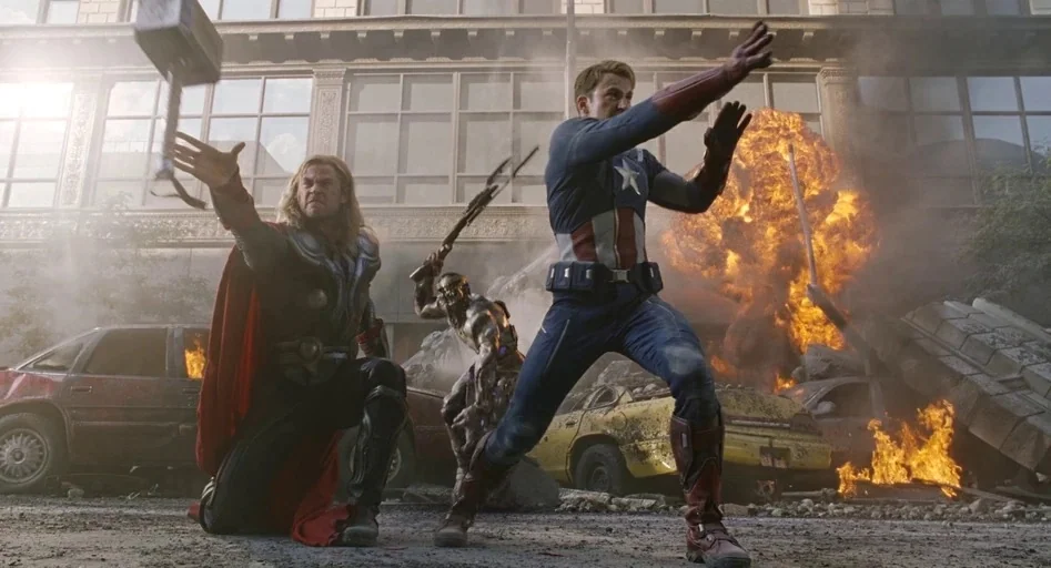 The Avengers (2012) movie still: fullbody — A war-torn metropolitan street filled with smoke, debris, and burning wreckage of civilian vehicles. The…