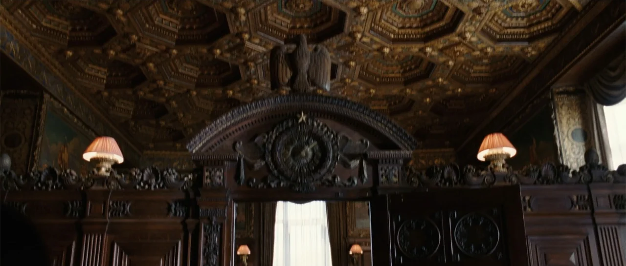Inside Man (2006) movie still: establishing — An opulent wood-paneled room features a highly ornate carved ceiling and an eagle crest. The space…