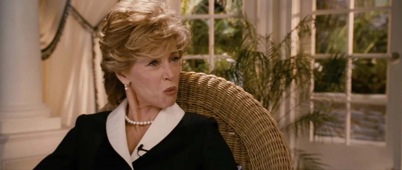 Monster-in-Law (2005) movie still: medium — A light-filled sunroom features wicker furniture and large windows with white grid panes. A blonde woman…