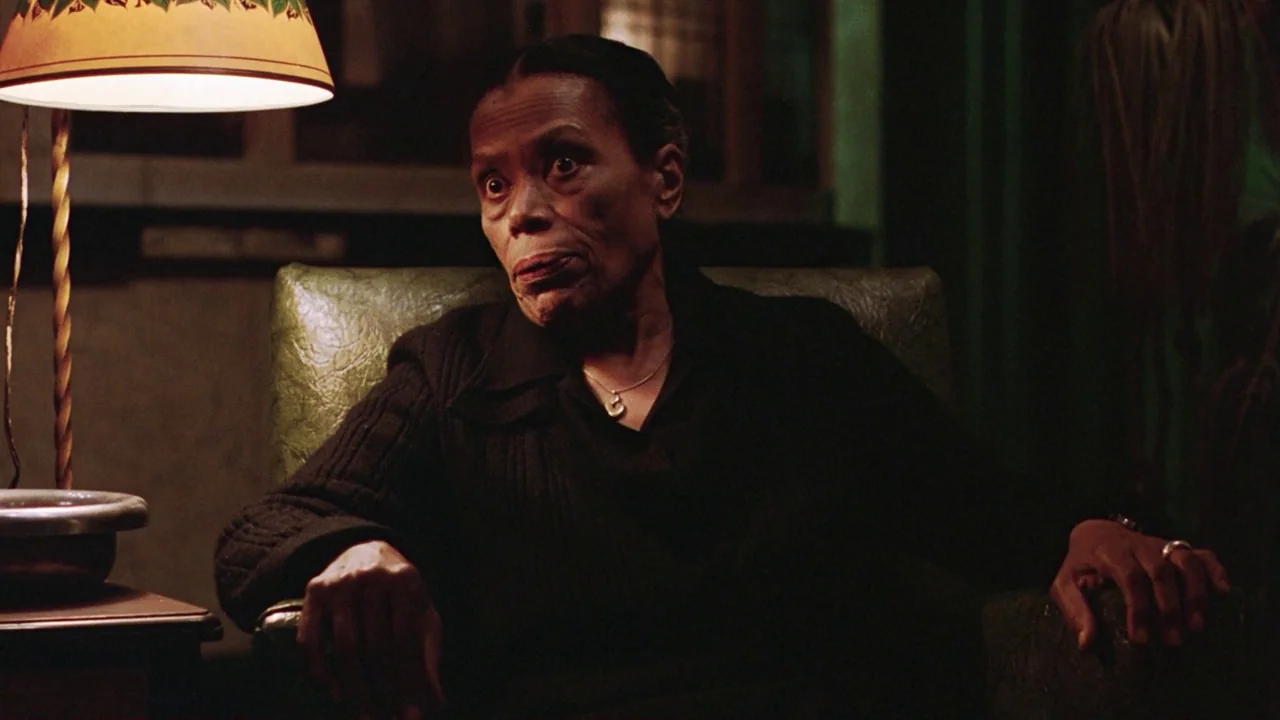 Being There (1979) movie still: medium — A dimly lit room features a woman seated in a green patterned armchair. A warm lamp provides a strong…
