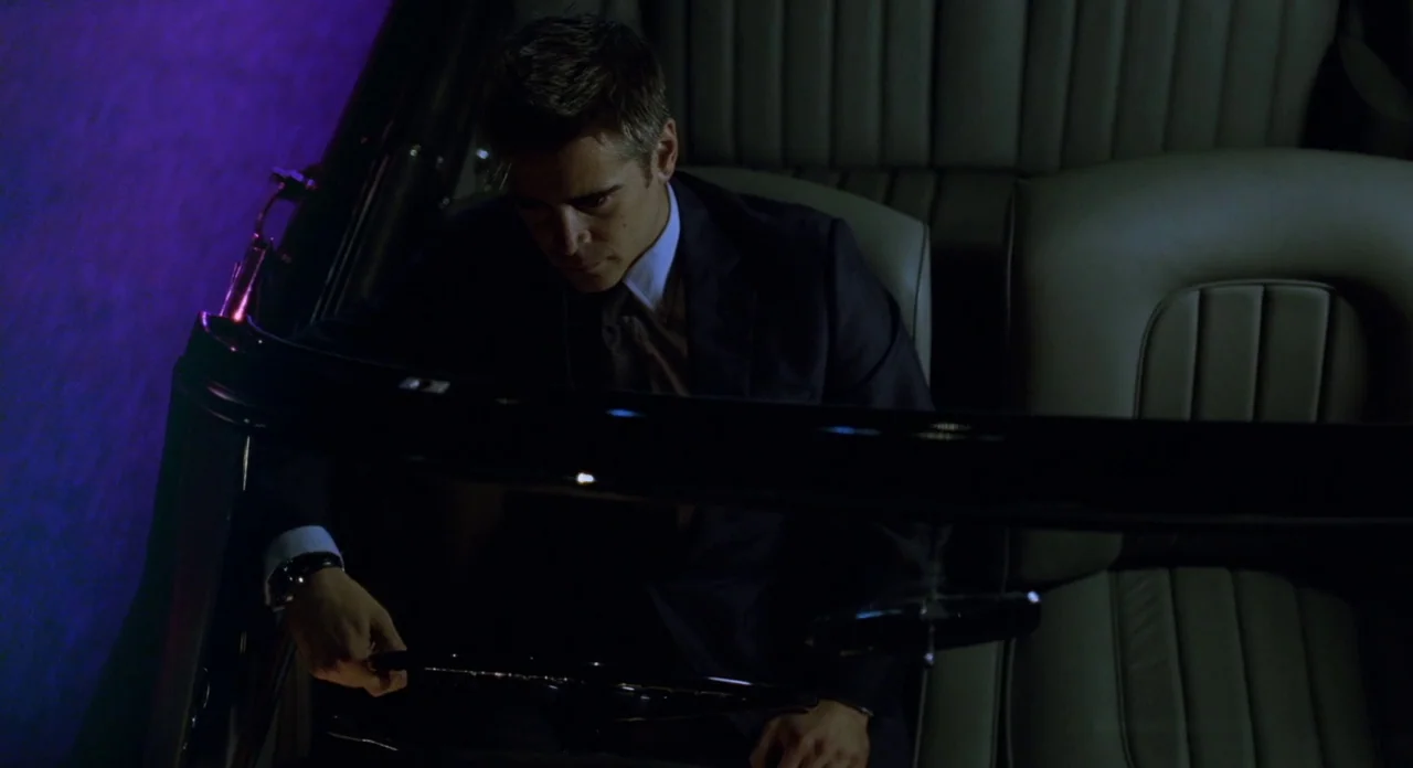 London Boulevard (2010) movie still: medium — A man sits inside a dark vehicle illuminated by faint purple neon street light. The interior features…