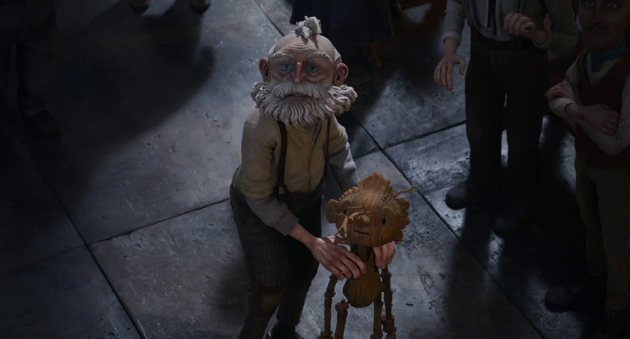 Guillermo del Toro’s Pinocchio (2022) movie still: medium — A dimly lit interior with a cold stone floor and surrounding observers. An elderly man…