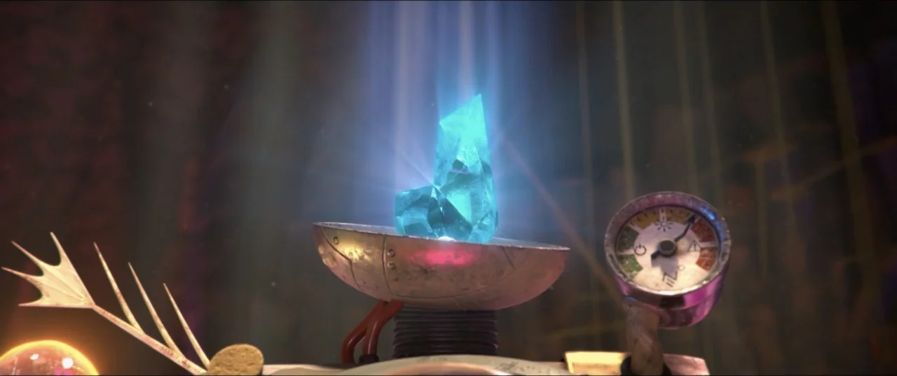 Scarygirl (2023) movie still: closeup — A metallic mechanical device holds a glowing blue crystal in a dimly lit laboratory. The device features a…