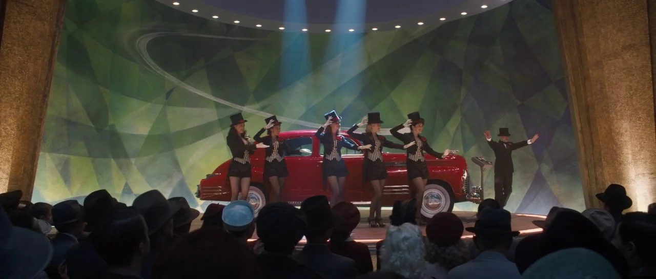 Captain America: The First Avenger (2011) movie still: wide — A performance stage features a red 1940s car before a green geometric backdrop. Five…