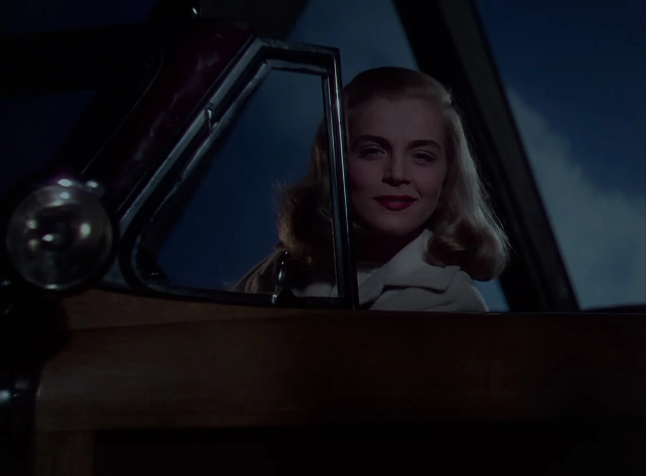Desert Fury (1947) movie still: closeup — A blonde woman sits in the driver seat of a vehicle at night. She looks directly toward the camera through…
